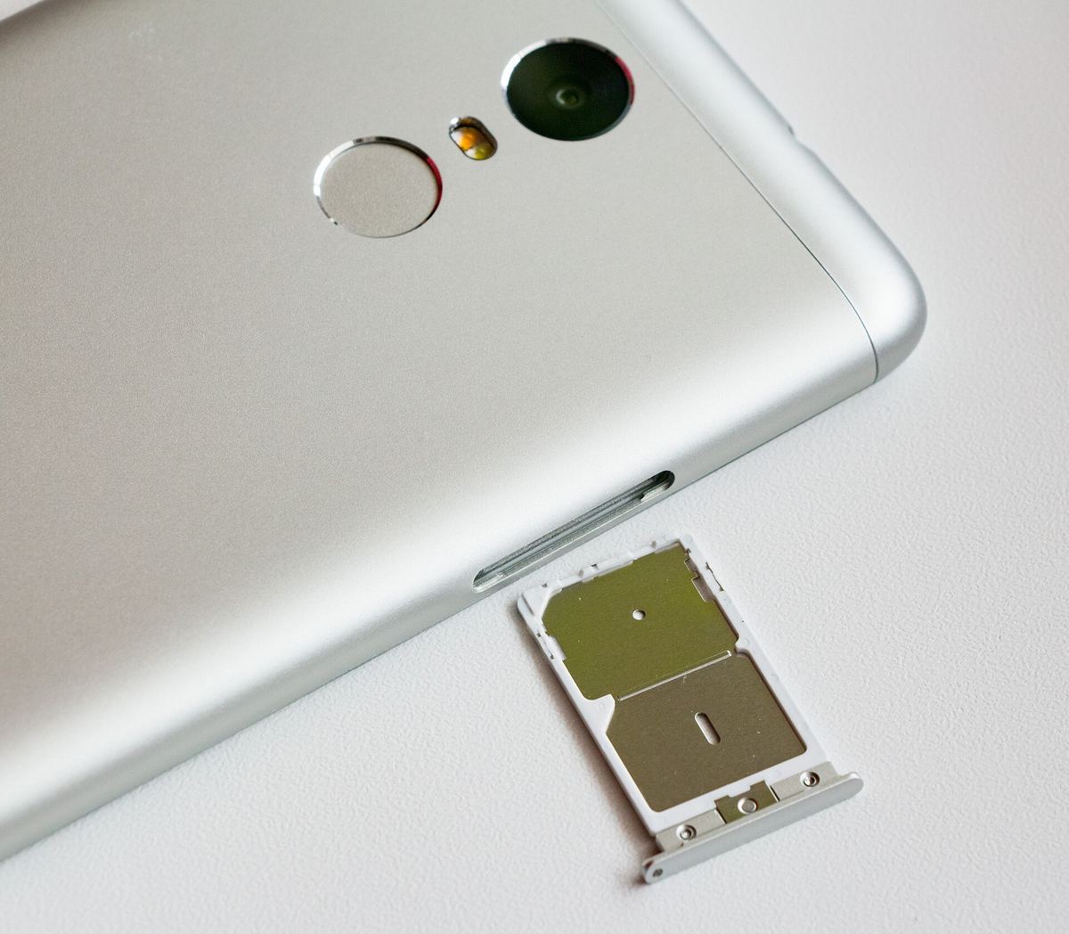 A SIM card held near a phone's SIM tray.